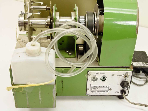 Side view of TP-125mk2 interior showing fluid reservoir bottle, clear tubing loop, and rear control panel