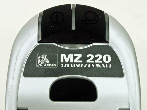 Zebra MZ220 top panel close-up showing Zebra logo badge, model designation, and two control buttons
