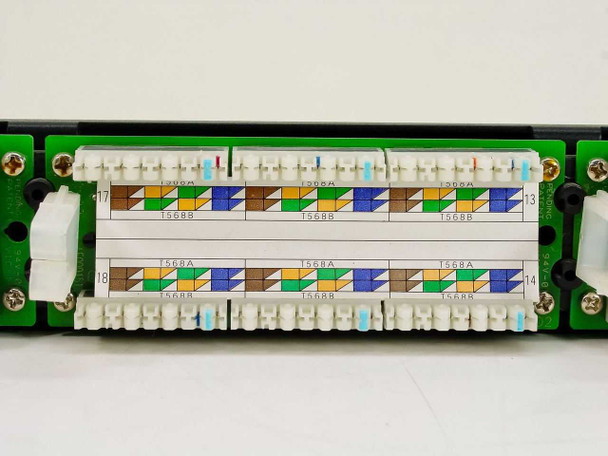 Close-up of rear IDC punch-down terminals on Dynacom CAT 5e patch panel showing T568A and T568B color-coded wiring diagrams on ports 13-18