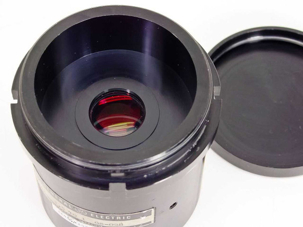 General Electric GS-028 projector lens top-down view into barrel showing internal red-coated glass element, with one lens cap beside it