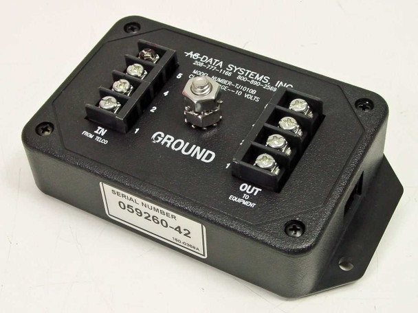 AC Data Systems TJ1010B surge suppressor – top view showing IN from telco and OUT to equipment terminal blocks, central ground stud, and serial number label 059260-42