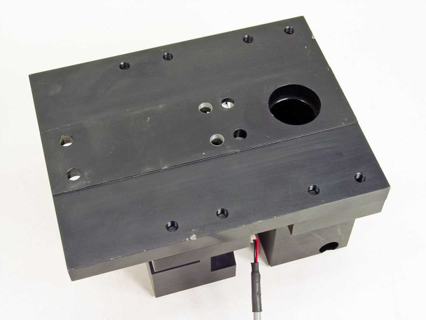 Top-down view of electronic shutter assembly baseplate showing mounting hole pattern, cable exit slot, and circular optical aperture cutout