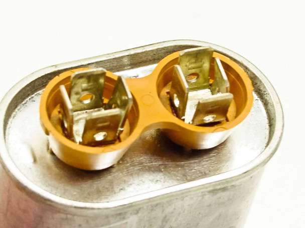 Dayton 4X429A oil capacitor — top-down view of dual terminal wells with quick-connect brass terminals