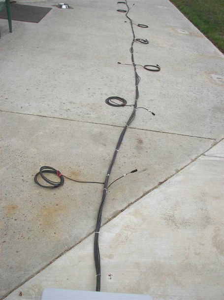 First Solar 10-string MC3 wiring harness fully laid out on concrete driveway showing full length of all ten individual string wires with connectors spread out