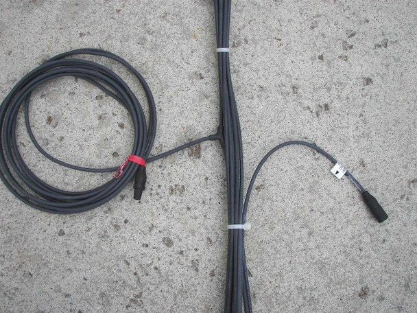 Close-up of MC3 cable connectors on First Solar wiring harness — red-banded common wire coiled separately on left, individual string wires with male MC3 connectors bundled on right