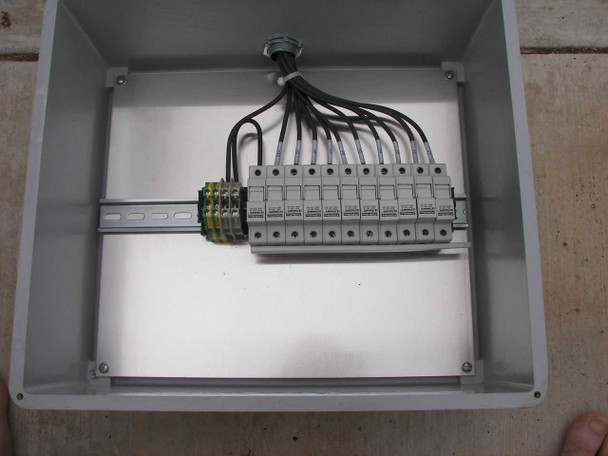Interior of First Solar combiner box — DIN rail with 11 Ferraz Shawmut ULTRASAFE fuse holders installed, black wiring routed to each holder, knockout fitting visible at top