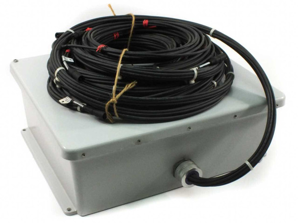 First Solar fused combiner box closed — gray outdoor-rated plastic enclosure with cable entry fitting on front face and bundled MC3 wiring harness on top, right-side view