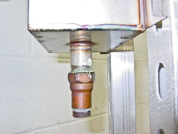 Underside view of Nortec 1502089 USD manifold showing steam outlet connection fitting and manifold header block