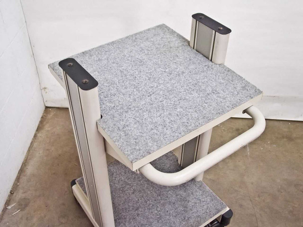 Top-down view of carpeted top shelf on white rolling cart showing shelf surface and corner column brackets