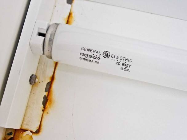 Close-up of GE Chroma 50 fluorescent lamp — labeled F20T12-050, 20 Watt, U.S.A. — rust/corrosion visible on fixture bracket
