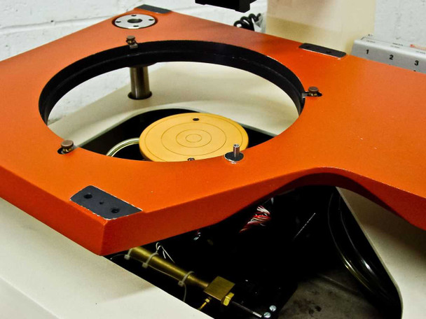 Rucker & Kolls 1032 orange stage top view — 9.75-inch circular opening with yellow/orange vacuum wafer chuck inside; microscope mount arm visible at upper left