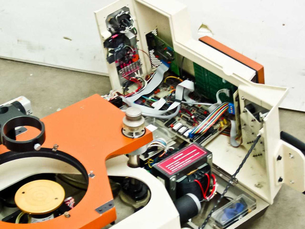 Rucker & Kolls 1032 interior with cover panel open — PCB control boards, ribbon cable harnesses, power module with red caution label, and wiring visible; orange stage and wafer chuck in background
