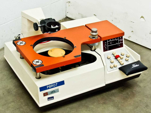 Rucker & Kolls 1032 Xynetics Stepping Wafer Prober — front 3/4 view showing orange stage, circular wafer chuck, control keypad panel on right, and microscope arm mount upper left; PBR07 asset tag label on front