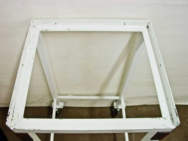 Top-down view of white cart showing open rimmed top shelf frame and two swivel castors visible at the rear