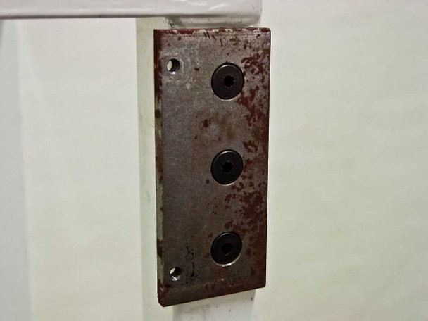 Close-up of rust-covered steel mounting plate on cart corner post with three recessed bolt holes