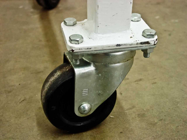 Close-up of swivel castor mounted to white cart leg showing rubber wheel, zinc-plated swivel bracket, and four hex bolts on mounting plate