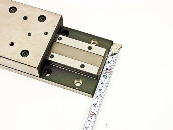 Linear slide micropositioner stage with measuring tape showing approximately 5.25 inch travel range of extended carriage
