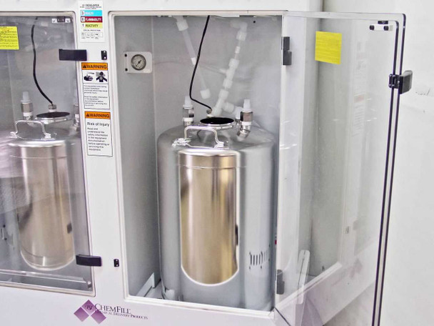 Interior view of FSI ChemFill cabinet with Canister B door open showing stainless steel tank, tubing manifold overhead, pressure gauge, and safety warning labels