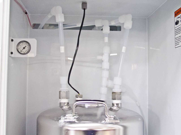 Close-up of stainless steel canister top inside FSI ChemFill bay showing polypropylene tubing connections and liquid level sensor wire