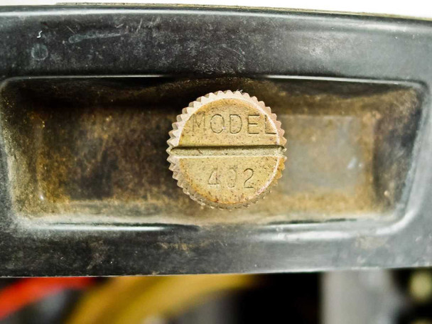 Close-up of Wheelco Model 402 model identification disc showing stamped brass medallion reading MODEL 402