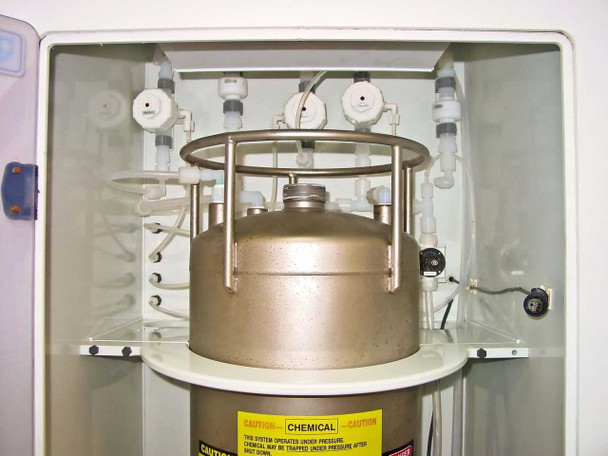 Interior view of Systems Chemistry day tank enclosure with stainless steel pressure tank, circular support ring, and pneumatic valve/tubing connections at top