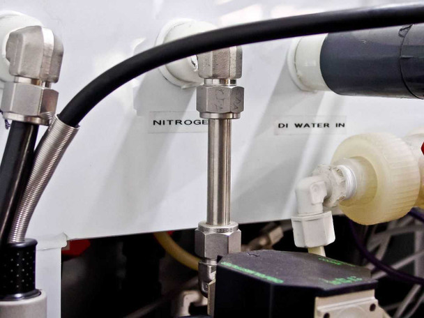 Close-up of nitrogen and DI Water In inlet fittings labeled on white panel surface with stainless steel compression fittings and tubing connections