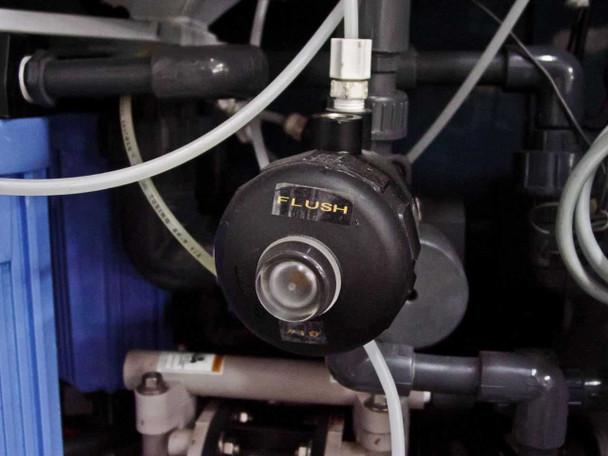 Close-up of Flush pump/valve showing diaphragm pump labeled FLUSH in yellow text with blue filter canister and tubing