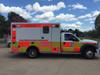 Ambulance with Fluorescent Yellow and Red ORACAL® 7510: A modern ambulance outfitted with a high-visibility design using fluorescent yellow and red vinyl from the ORACAL® 7510 series. The body features bold fluorescent yellow panels along the sides, with fluorescent red chevron stripes on the rear doors for added visibility. The reflective neon colors ensure the vehicle remains noticeable in both daylight and poor lighting, enhancing its emergency response presence. The ambulance's design prioritizes safety and quick recognition, crucial for navigating through busy streets and intersections.