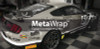 A Ford Mustang being wrapped with vibrant, high-quality vinyl film. The vehicle is undergoing a transformation with a sleek, glossy finish that highlights its bold curves and aerodynamic design. The wrap is being carefully applied to the body of the car, showcasing the precision and skill needed for a flawless application over the Mustang’s curves, vents, and contours. The graphic design features sharp, striking lines, and the vibrant color contrasts beautifully against the car’s original paint, giving it a fresh, eye-catching look.