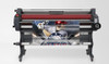 Image of the Mimaki LA-160W laminator in a production setting applying clear laminate to wide-format printed graphics, showing heated top roller and control panel interface.