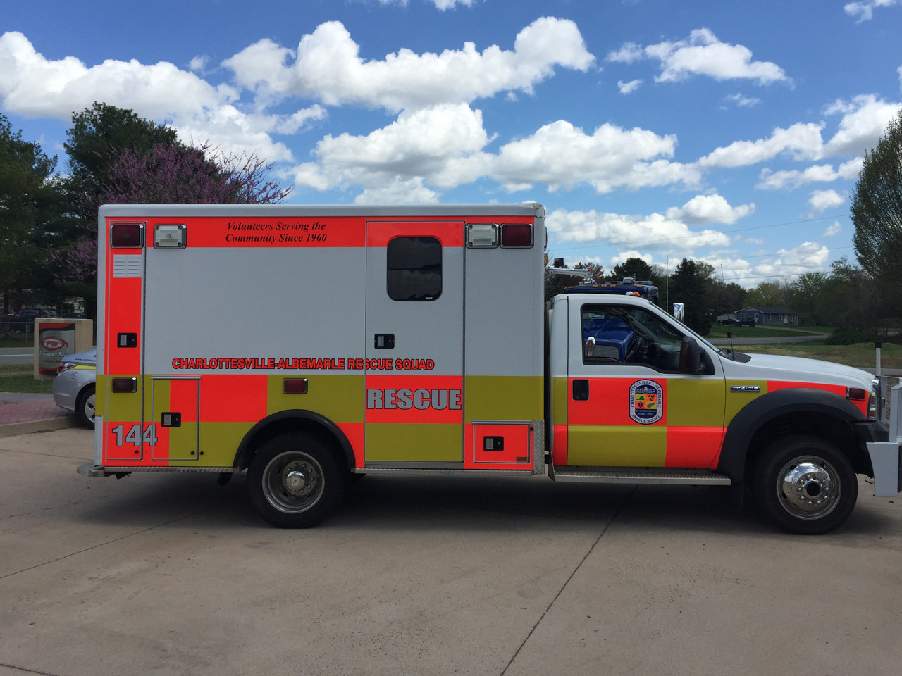 Ambulance with Fluorescent Yellow and Red ORACAL® 7510: A modern ambulance outfitted with a high-visibility design using fluorescent yellow and red vinyl from the ORACAL® 7510 series. The body features bold fluorescent yellow panels along the sides, with fluorescent red chevron stripes on the rear doors for added visibility. The reflective neon colors ensure the vehicle remains noticeable in both daylight and poor lighting, enhancing its emergency response presence. The ambulance's design prioritizes safety and quick recognition, crucial for navigating through busy streets and intersections.