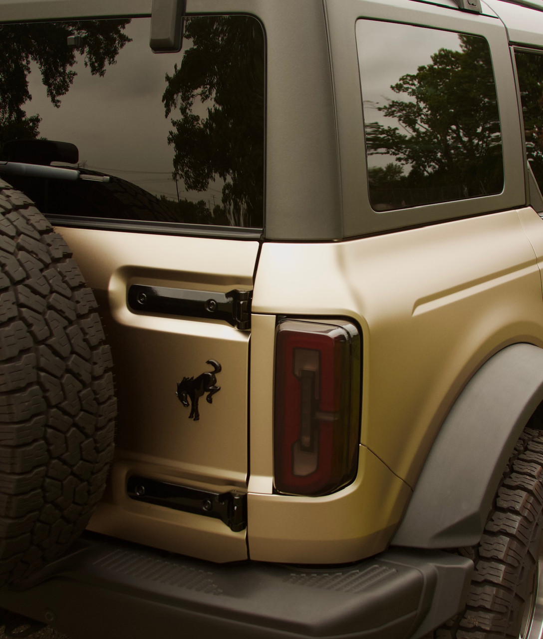 Close-up Image: A close-up of the rear end of a Ford Bronco wrapped in KPMF Matte Dune Metallic, highlighting the seamless finish and depth of color in natural light. Close-up Image: A close-up of the rear end of a Ford Bronco wrapped in KPMF Matte Dune Metallic, highlighting the seamless finish and depth of color in natural light.