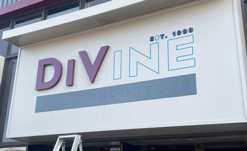 A roll of Metamark MM-BM Blue Paint Mask Film on a cutting table beside a vinyl plotter — ideal for producing custom stencil graphics, logos, and detailed paint masks for signage and décor projects.