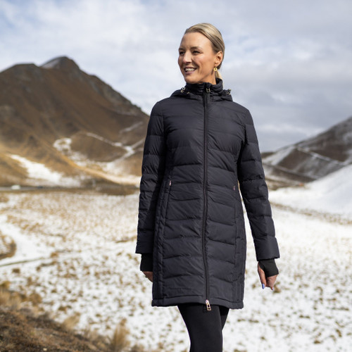 Woman wearing Moke - Sydney Cloud Touch 90/10 Down Coat (SYDNEY) in the colour Black on a hill with snow in the background.