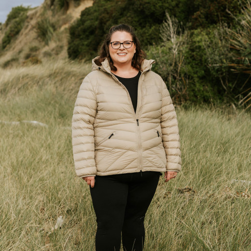 Woman wearing Moke - Cushla Packable Down Jacket (CUSHLA) in the colour Palomino walking through grass.