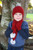 Child wearing beanie, scarf and glove combo with pom pom. Colour Red