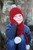 Child with hand on face wearing beanie. Colour Red