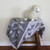 Baby cot blanket in colour silver and off white, on chair.