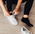 Woman putting on shoes wearing black sneaker socks Woman putting on shoes wearing black sneaker socks