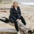 Woman wearing Moke - Sydney Cloud Touch 90/10 Down Coat (SYDNEY) in the colour Black on a beach with sand in the background.