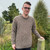 Man leaning on fence wearing Lesley Unisex Aran Wool sweater in the colour Brown.