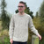 Man leaning on fence wearing Lesley Unisex Aran Wool sweater in the colour Oatmeal.