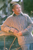 Man leaning on fence wearing Lesley Unisex Aran Wool sweater in the colour Brown.