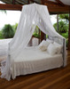 Round natural cotton bed canopy over a Queen bed