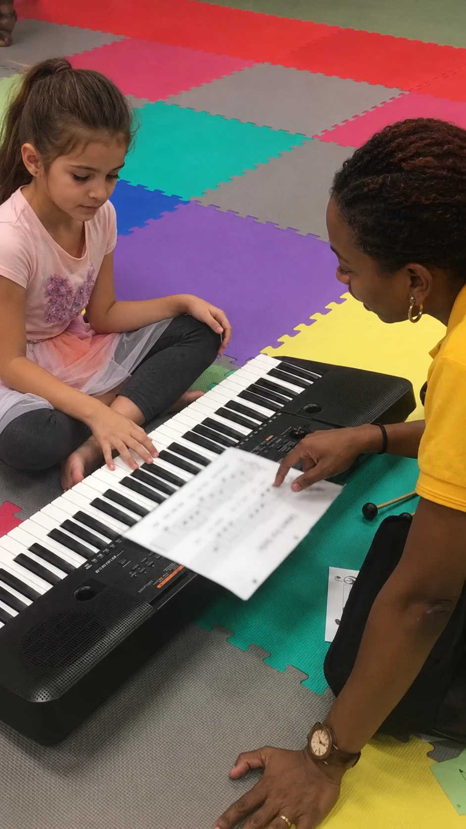 Child reading music beside keyboard