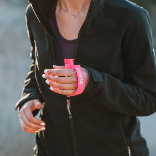 A person running while having a neon colored pepper spray strap around their hand.