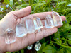 Several medium-sized clear quartz crystal point generators lie across an open palm showing variations in size, shape, and clarity.