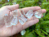 Several small-sized clear quartz crystal point generators lie across an open palm showing variations in size, shape, and clarity.
