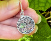 Sterling silver and abalone shell tree of life earrings dangle from French hook ear wires. These earrings are not just a statement of style but also a testament to inner strength, harmony, and spiritual elevation. .