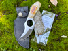 witch's circle boline lying on top of its protective sheath and a white sage smudge bundle with a ritual-sized incense stick.